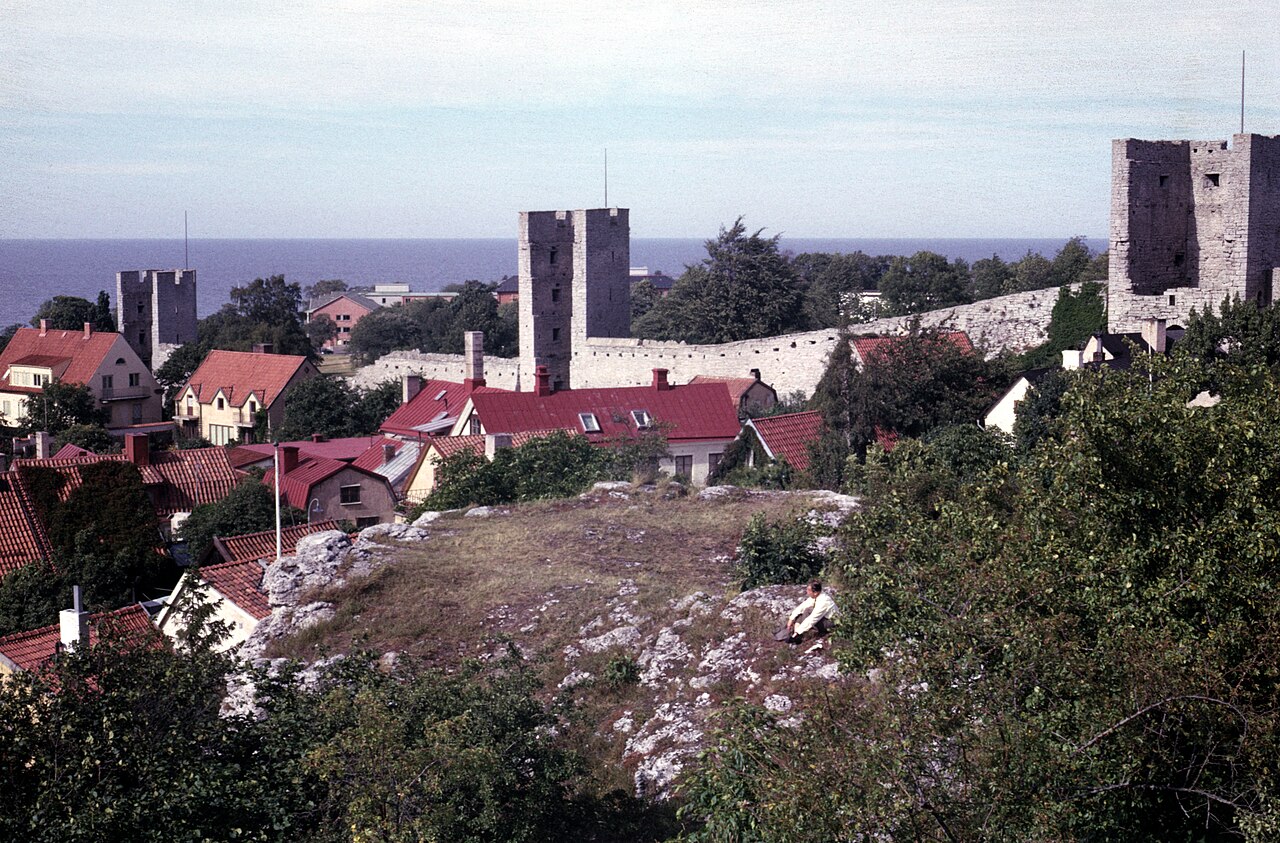 Kaupunki muurin takana — punaiset kattotiilet ja kirkontornit kohoamassa Ringmurenin takaa, näkymä, joka on määrittänyt Visbyn keskiajalta asti (arkistokuva, 1965; Andy Eick, CC BY 2.0).